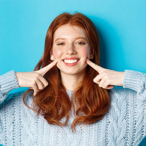 A woman pointing to her smile