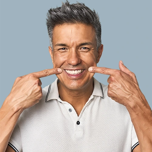 Man smiling and pointing to his new dental implants in his mouth.