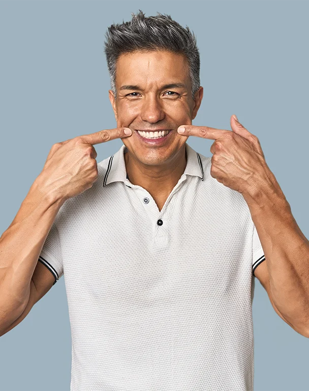 Middleaged man smiles pointing fingers at his dental bridge  work